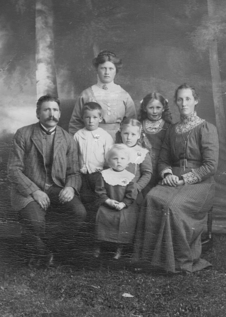 Johan Olov och Brita Märta med barnen Augusta, Olof, Betty och Märta samt piga. Förmodligen 1912 då yngsta barnet Märta är 2 år. Året efter dör de båda äldsta döttrarna.